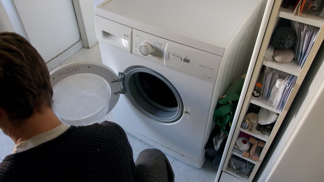 человек начинает загружать грязную одежду в стиральную машину дома