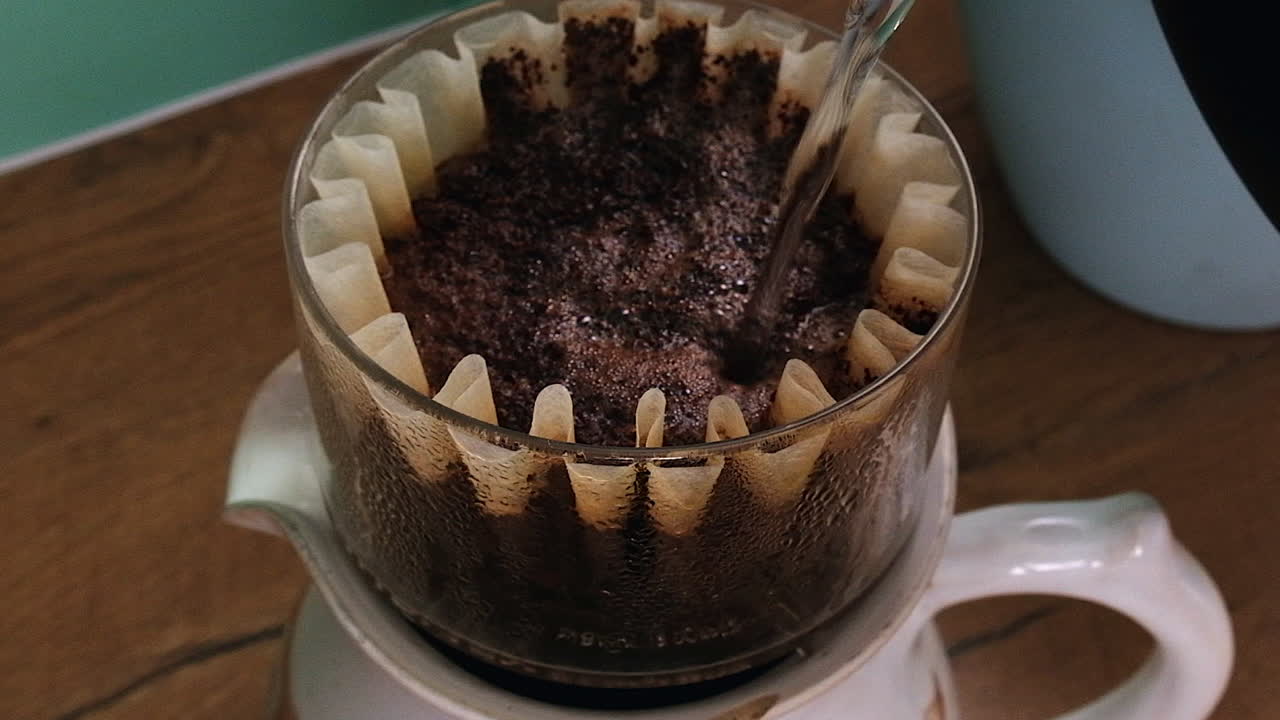 Hot water is poured onto rich dark ground coffee in basket filter
