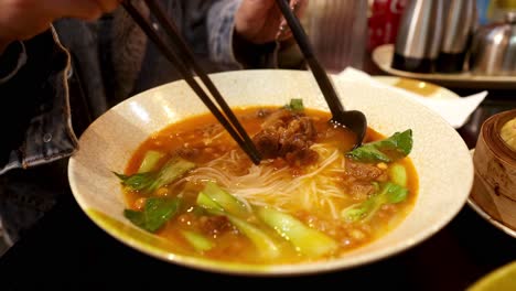 person enjoying ramen soup with chopsticks