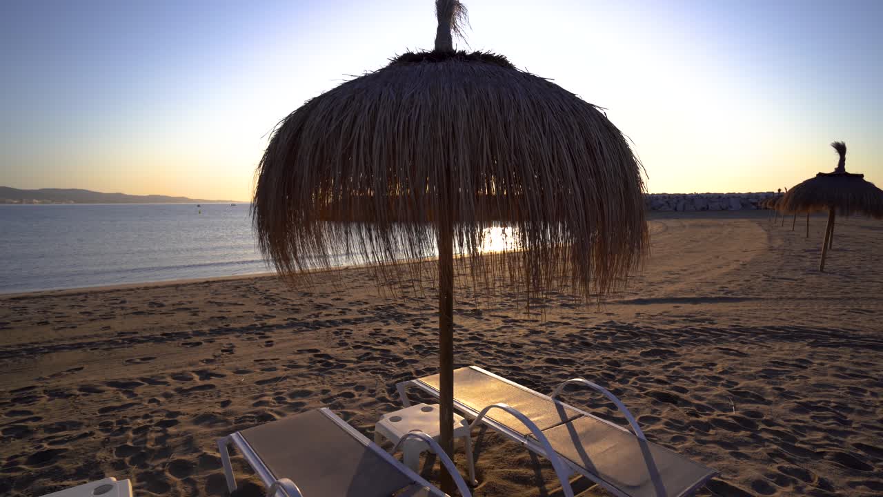 Puerto Banus beach straw beach umbrellas with sunbeds at sunrise, Luxury holiday inspiration Marbella, Malaga, Spain, shot on a gimbal in 4k
