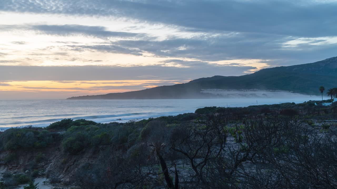 costa del océano con cielo al atardecer y niebla ligera, vista de lapso de tiempo
