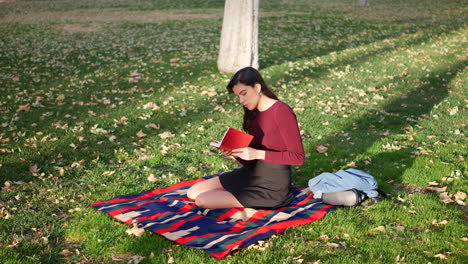 A-young-woman-school-girl-reading-a-book-on-a-campus-lawn-or-outdoor-park-SLOW-MOTION