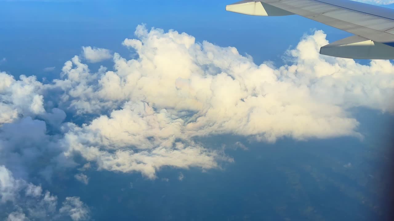 Airplane wing above soft white clouds in blue sky—perfect for travel, freedom, inspiration, or aerial background content