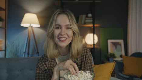 woman eating popcorn and watching movie at home