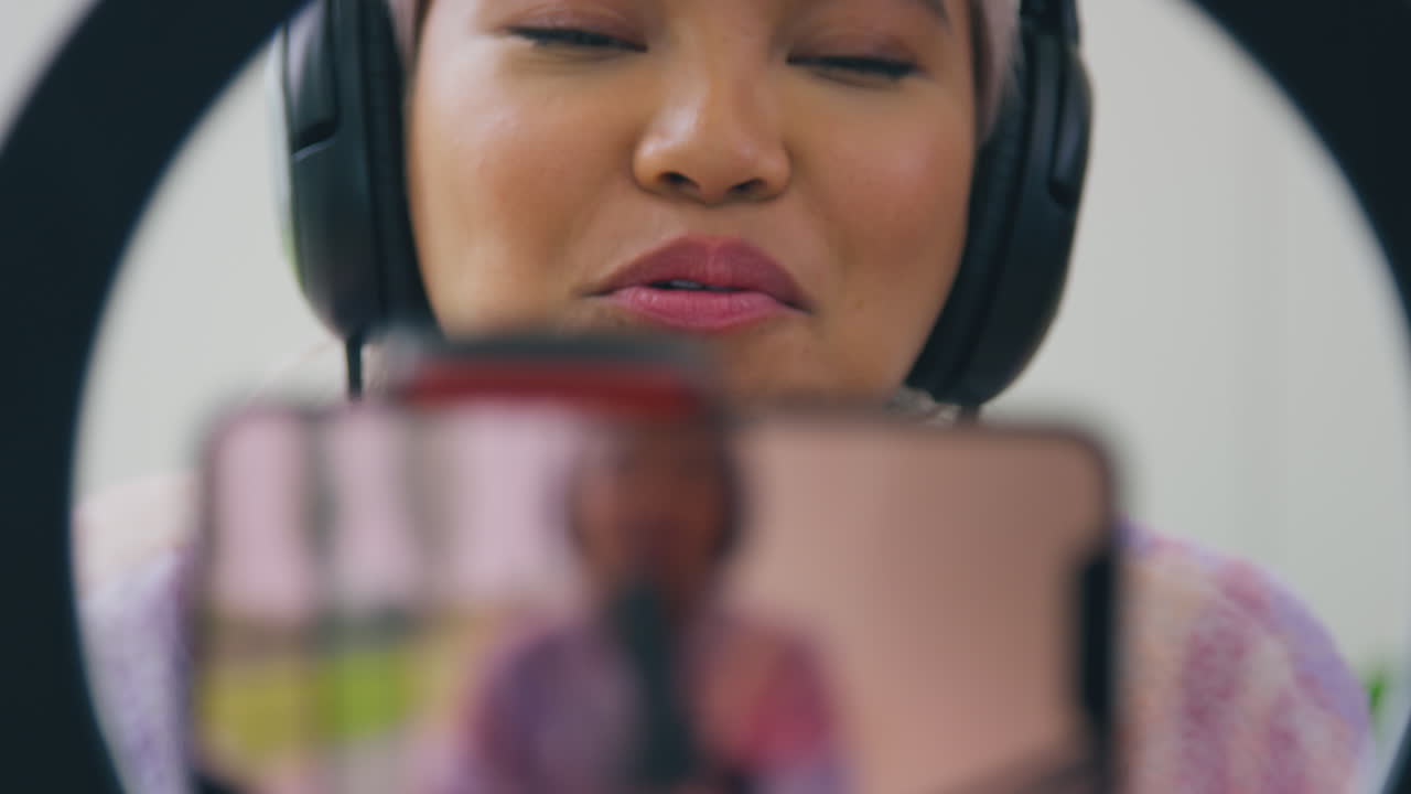 vlogger femenina con auriculares con micrófono transmitiendo en vivo en el teléfono móvil