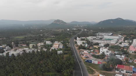 aerial flyover above an indian village surrounded by green nature forest and huge mountains