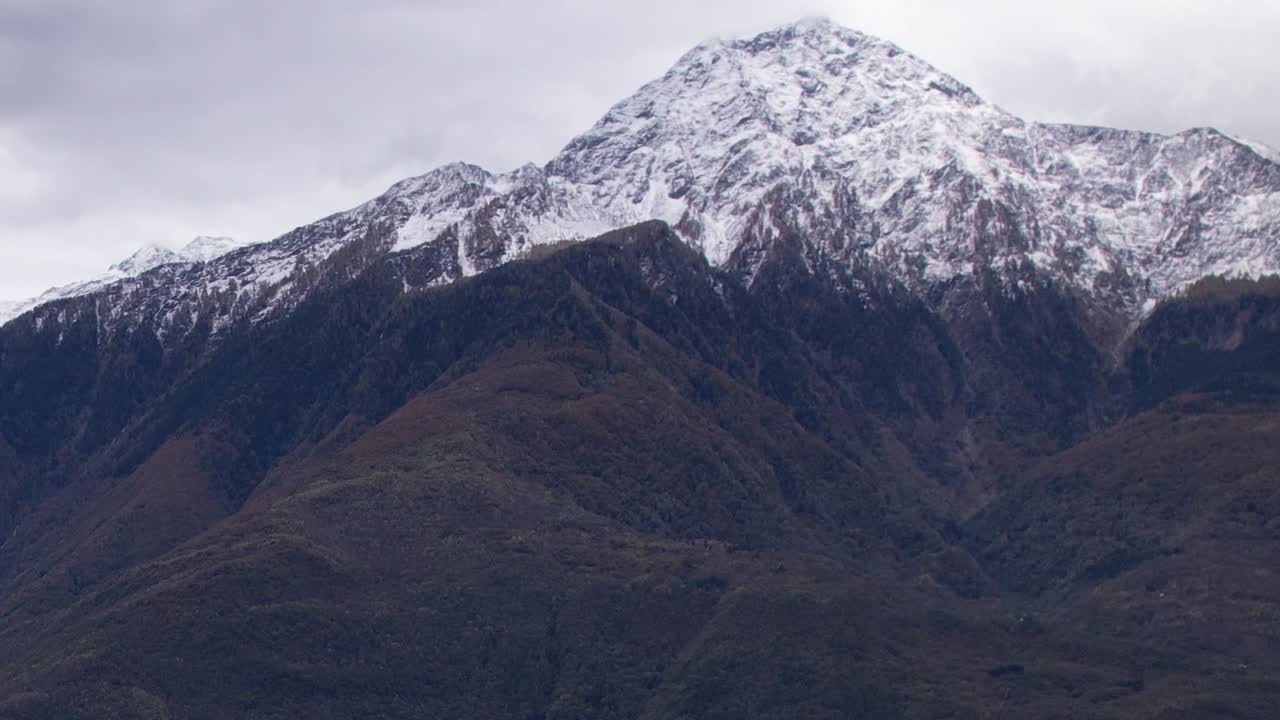 Majestic drone view of snow-capped Alps in Italy under cloudy sky