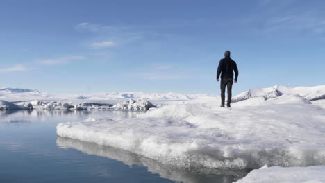 young male walking ice floe in beautiful glacial lagoon in iceland in slow motion