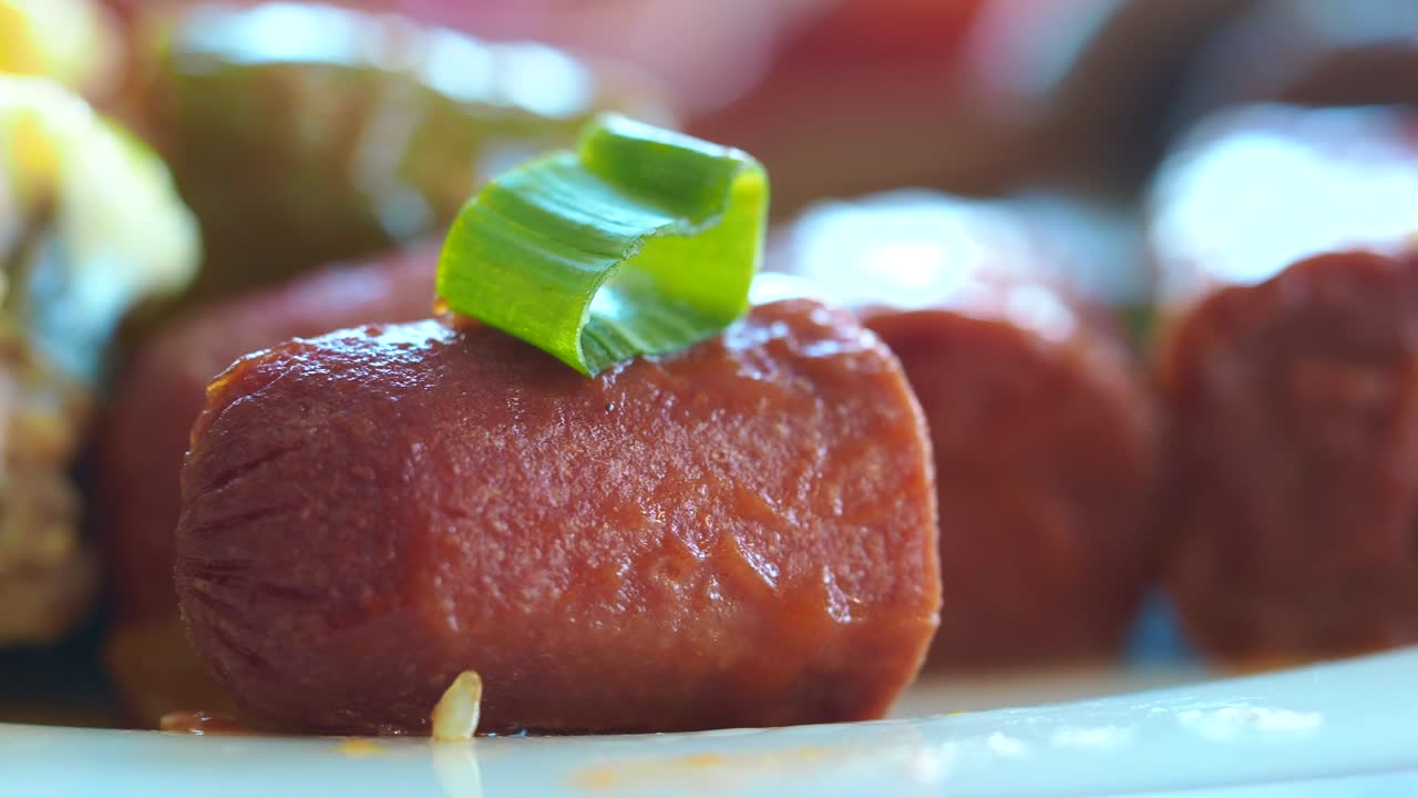 Close-up of a cooked mini sausage garnished with green onion