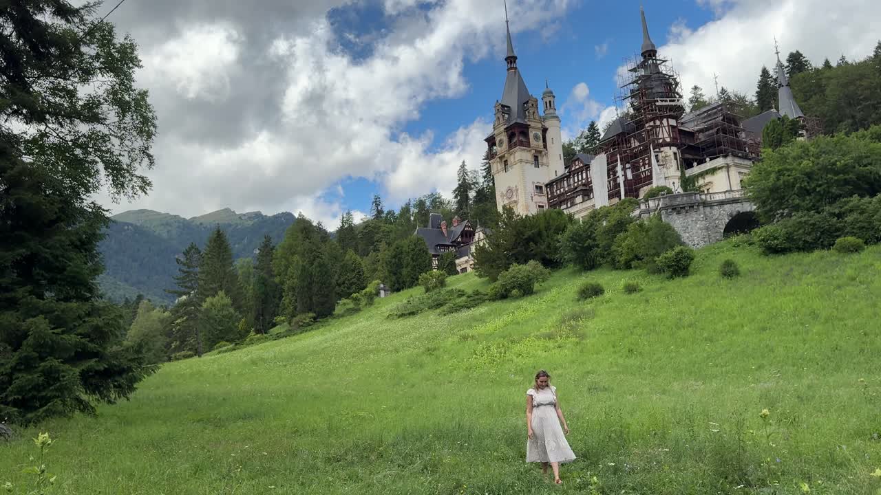 Young blonde woman walking towards the Castle of Peles in a fairytale scene