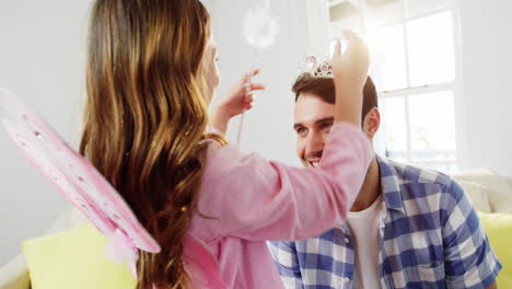 girl dressed up in a fairy costume placing tiara on fathers head