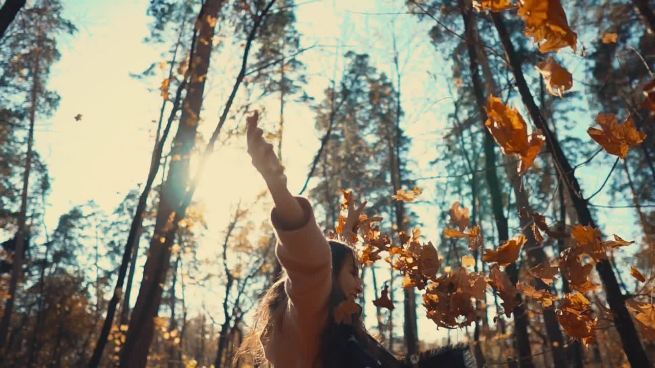 mujer disfrutando de las hojas de otoño en el bosque