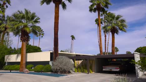 außenaufnahme eines modernen hauses in palm springs, kalifornien, mitte des jahrhunderts, mit klassischem retro-auto, das in garage 1 geparkt ist