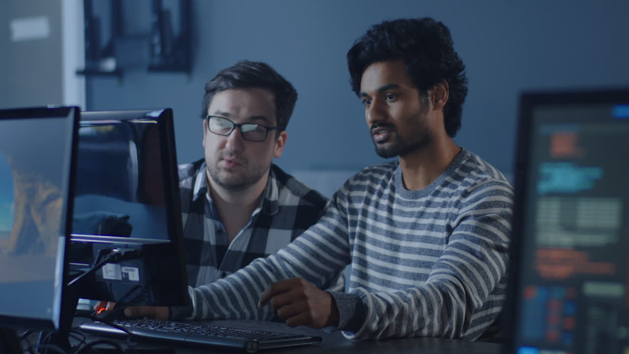 Two programmers working together at computers in a modern office.