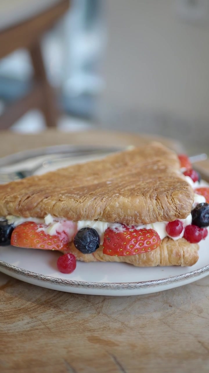 Croissant salato fresco con crema e frutti di bosco su un piatto.