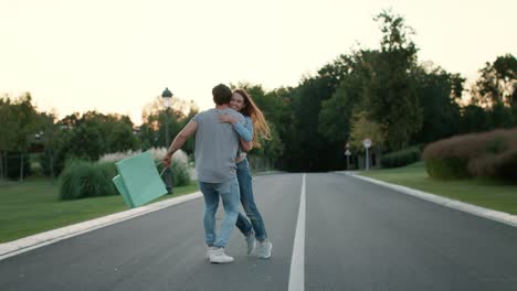 pareja joven divirtiéndose en el parque. hombre guapo girando chica en las manos al aire libre