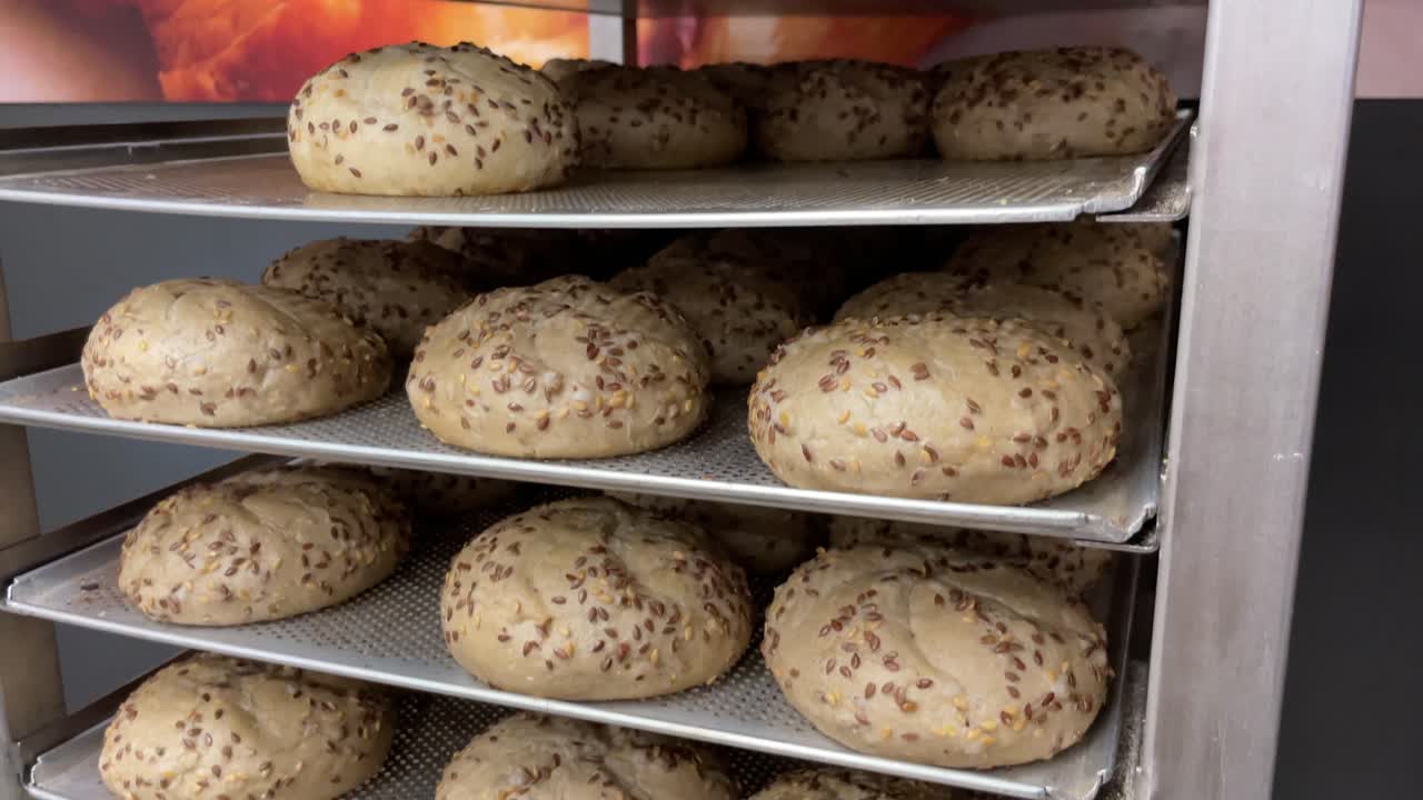 Uncooked raw breadsticks and buns sitting on bakery shelf rack to be put in oven