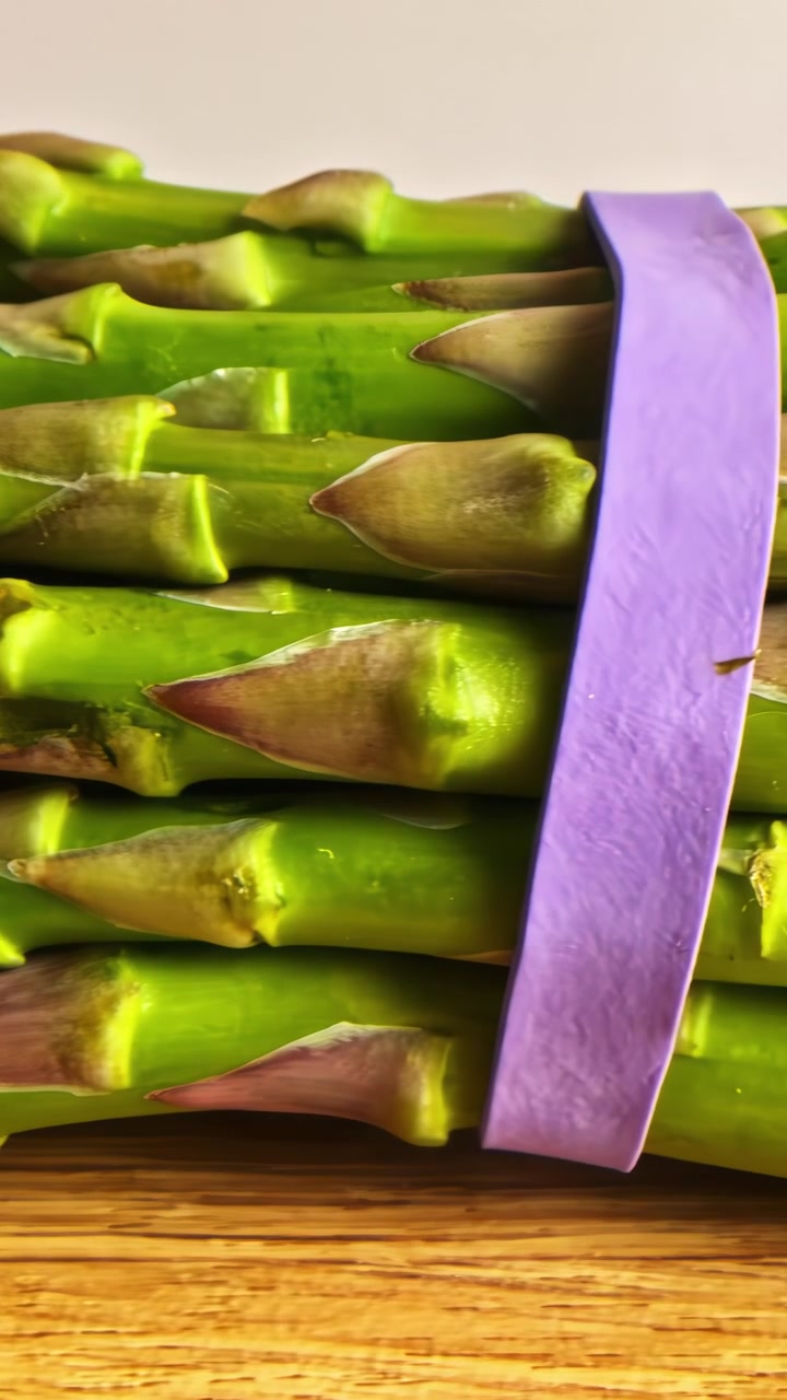 Mazzetto di asparagi verdi freschi con un elastico viola su un tavolo di legno