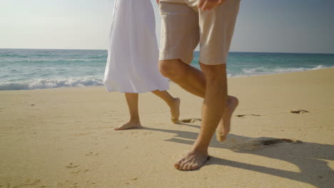 legs of couple walking on sandy beach