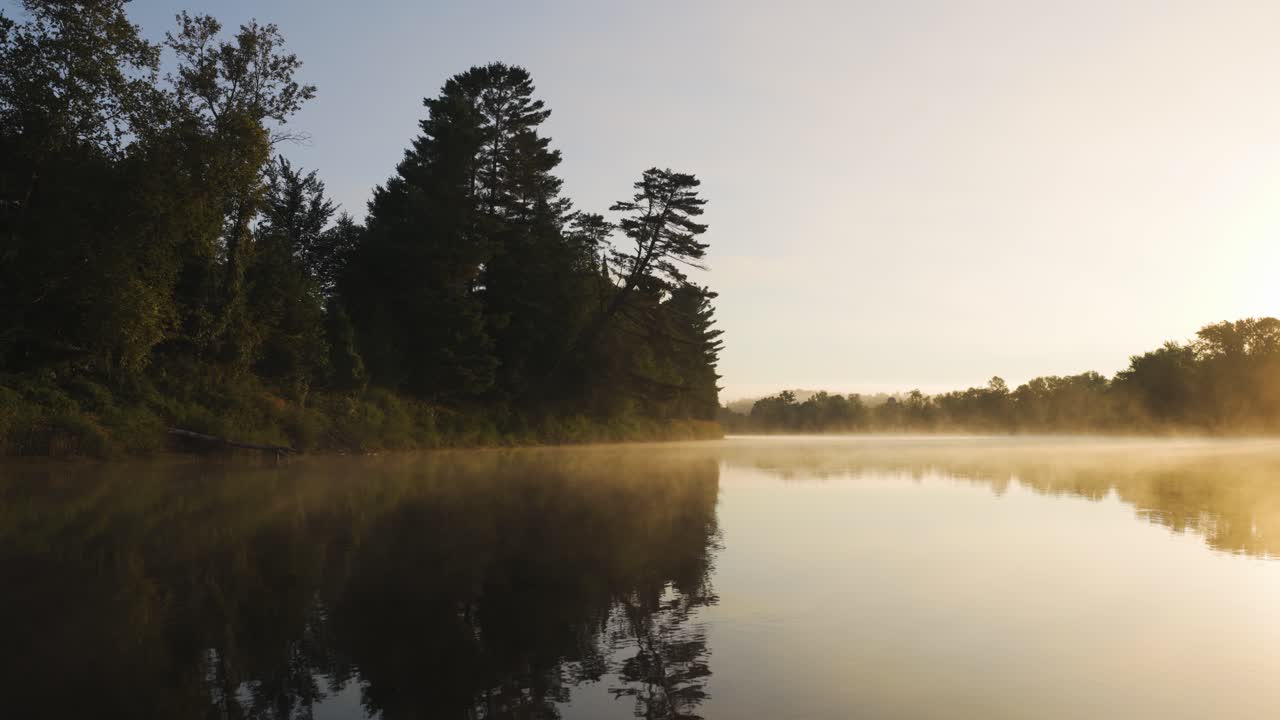 An early sunrise with rising haze over a gently flowing stretch of Canada's Gatineau River