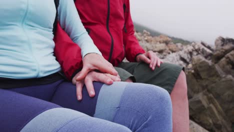 sección media de una pareja de excursionistas mayores con mochilas sentadas en las rocas