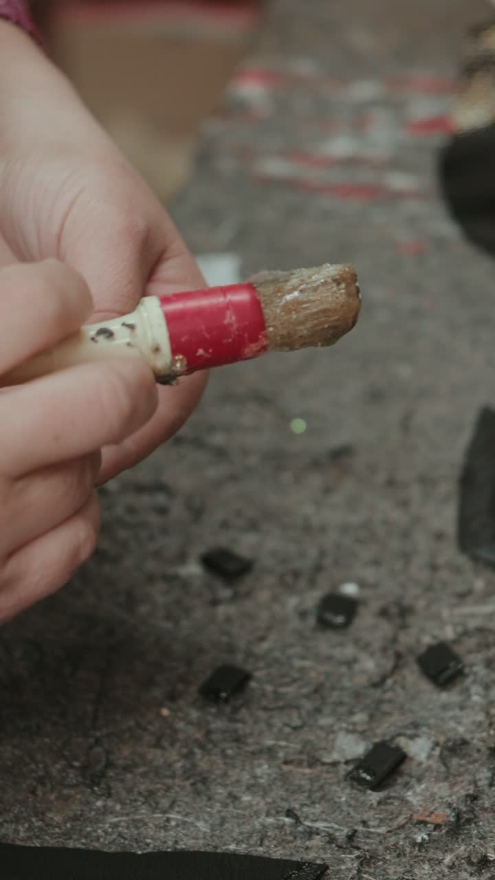 Vertical closeup of artisan gluing small components for handcrafted footwear production