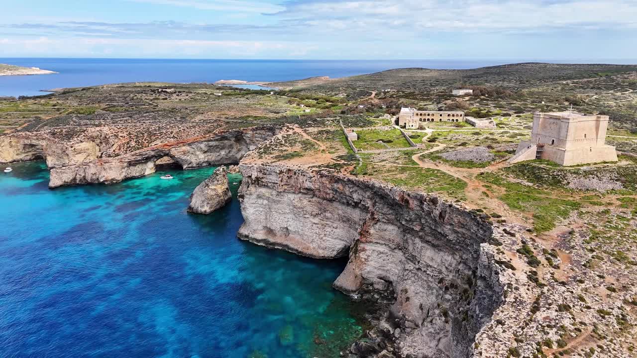 Cominon Għajnsielemin Maltan kalkkikivikalliot johtavat kohti Pyhän Marian tornia, vuoden 1618 Wignacourtin vartiotornia, josta on näkymä Cominon kanaalille ja Välimerelle, dronen eteenpäin suuntautuva ylilento.