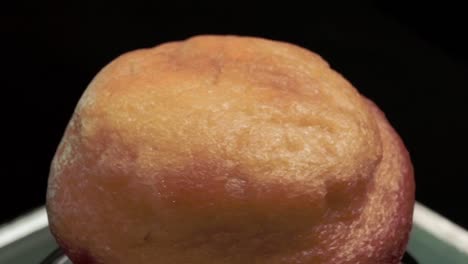 un primer plano de un muffin de color marrón dorado, con una textura suave, filmado en un entorno oscuro