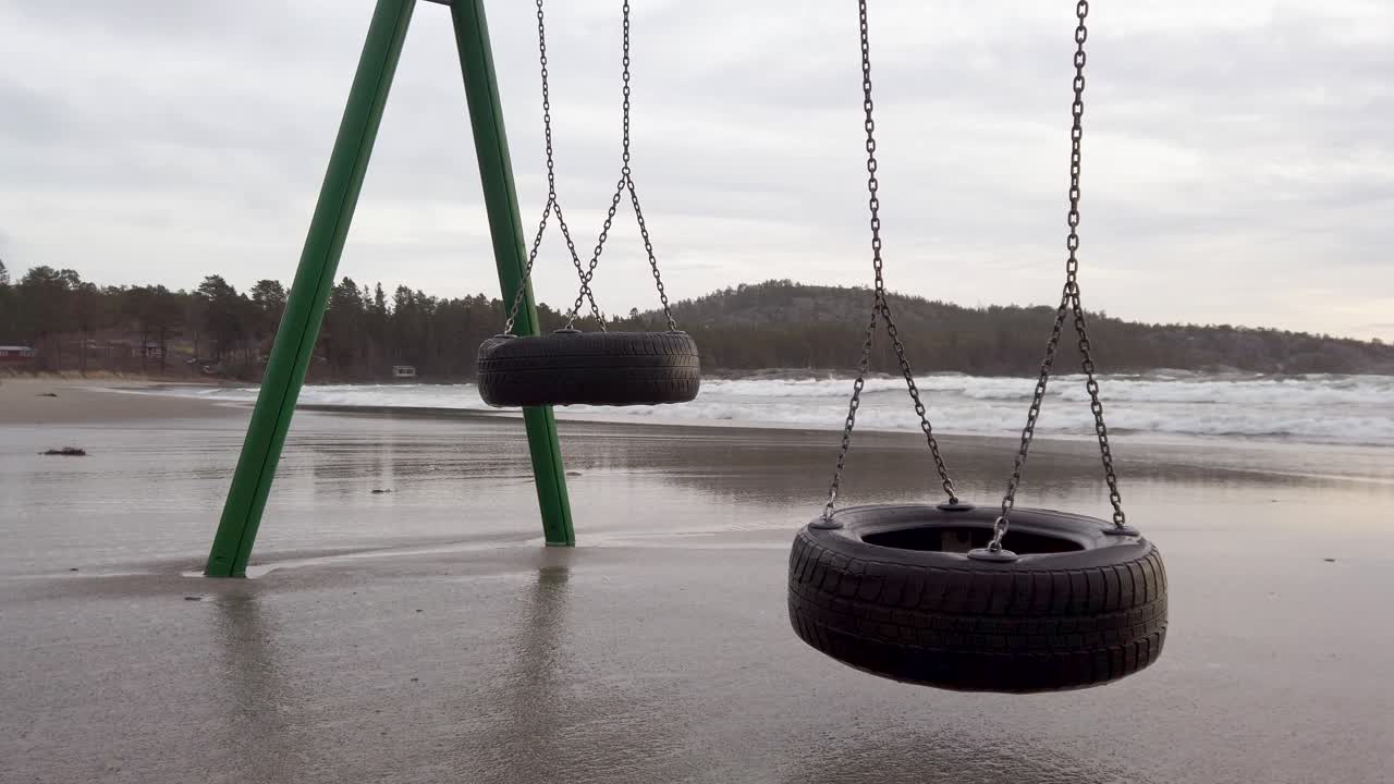 Closeup of swings moving slowly in the wind on a flooded beach