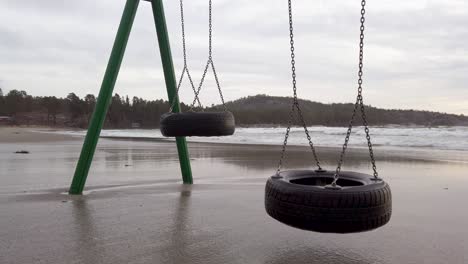 closeup of swings moving slowly in the wind on a flooded beach