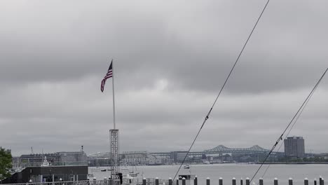 bandera de estados unidos ondeando en el viento en el puerto de boston en un día de verano nublado y nublado