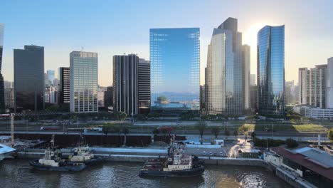 aerial dolly in of boats in puerto madero docks with high-rise skyscrapers at golden hour, buenos aires