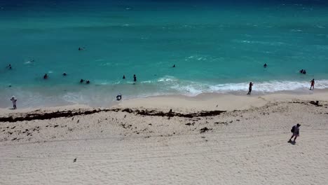 gente nadando en el mar caribe al mediodía y olas rompiendo en la costa