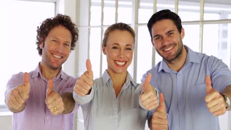 Gleeful-colleagues-showing-thumbs-up-to-camera-