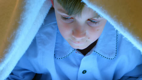 Front-view-of-Caucasian-boy-under-blanket-in-bedroom-at-comfortable-home-4k