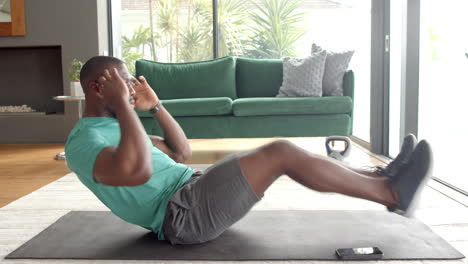 exercising on yoga mat, strong and fit man doing sit-ups at home gym