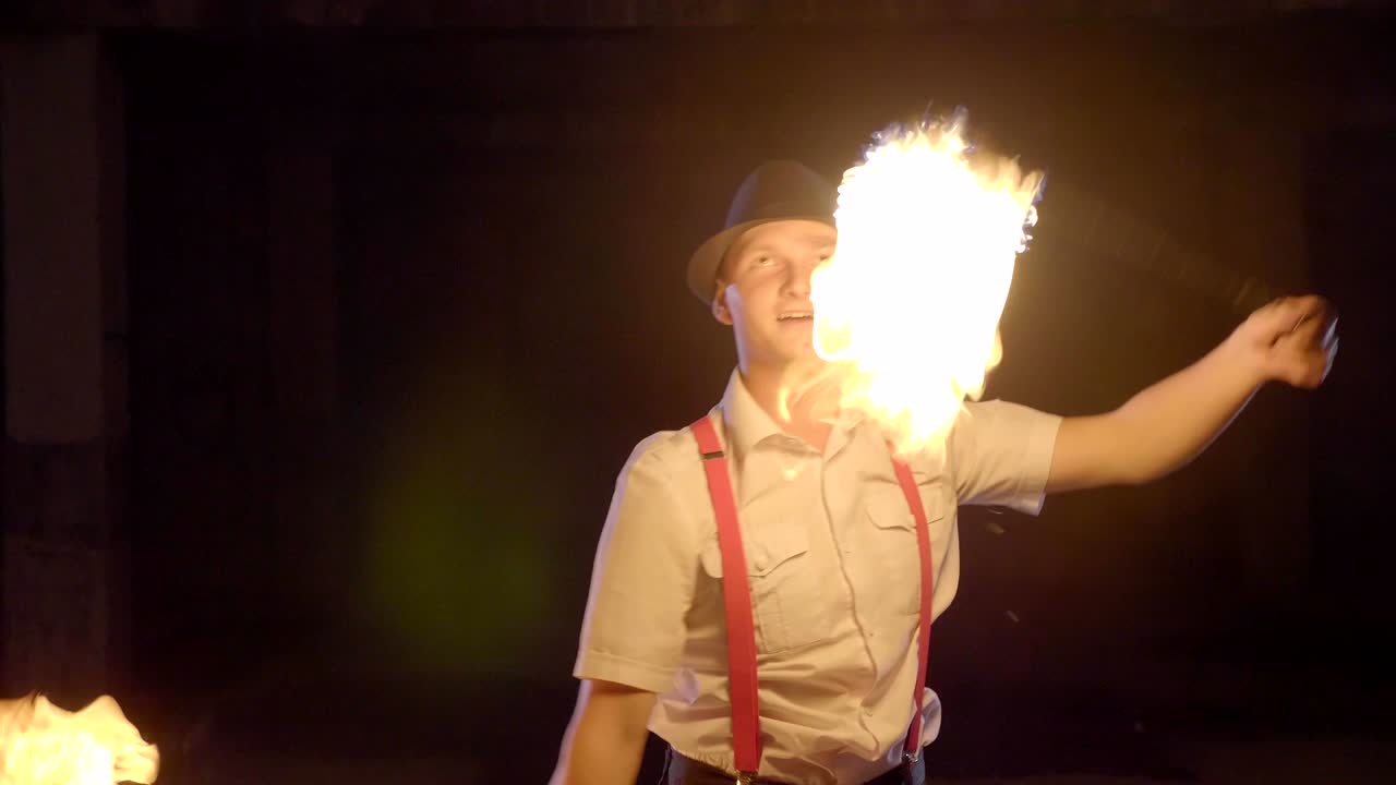 artista masculino realizando un espectáculo de fuego en la oscuridad en cámara lenta.