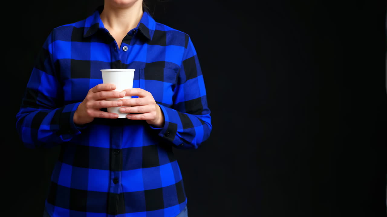 Mujer sosteniendo un vaso desechable blanco sobre fondo negro.
