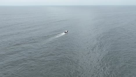 aerial panning shot of a boat sailing over the sea in the pacific ocean with calm waves on a sunny day