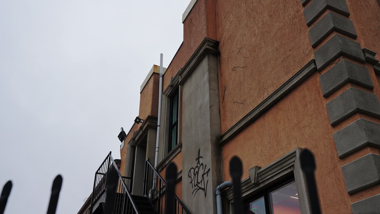 Parete esterna di un edificio a Whitby con una texture architettonica arancione dietro una recinzione nera, inquadratura panoramica lenta, Ontario, Canada.
