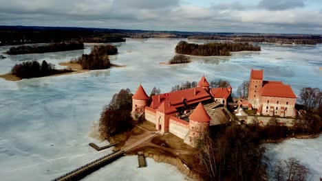 Trakai-Castte-Lithuania,-drone-shot-of-the-medieval-castle-in-a-frozen-lake-on-a-cloudy-day