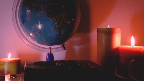 globe in flickering candles light background on a wooden surface with stones and ancient books