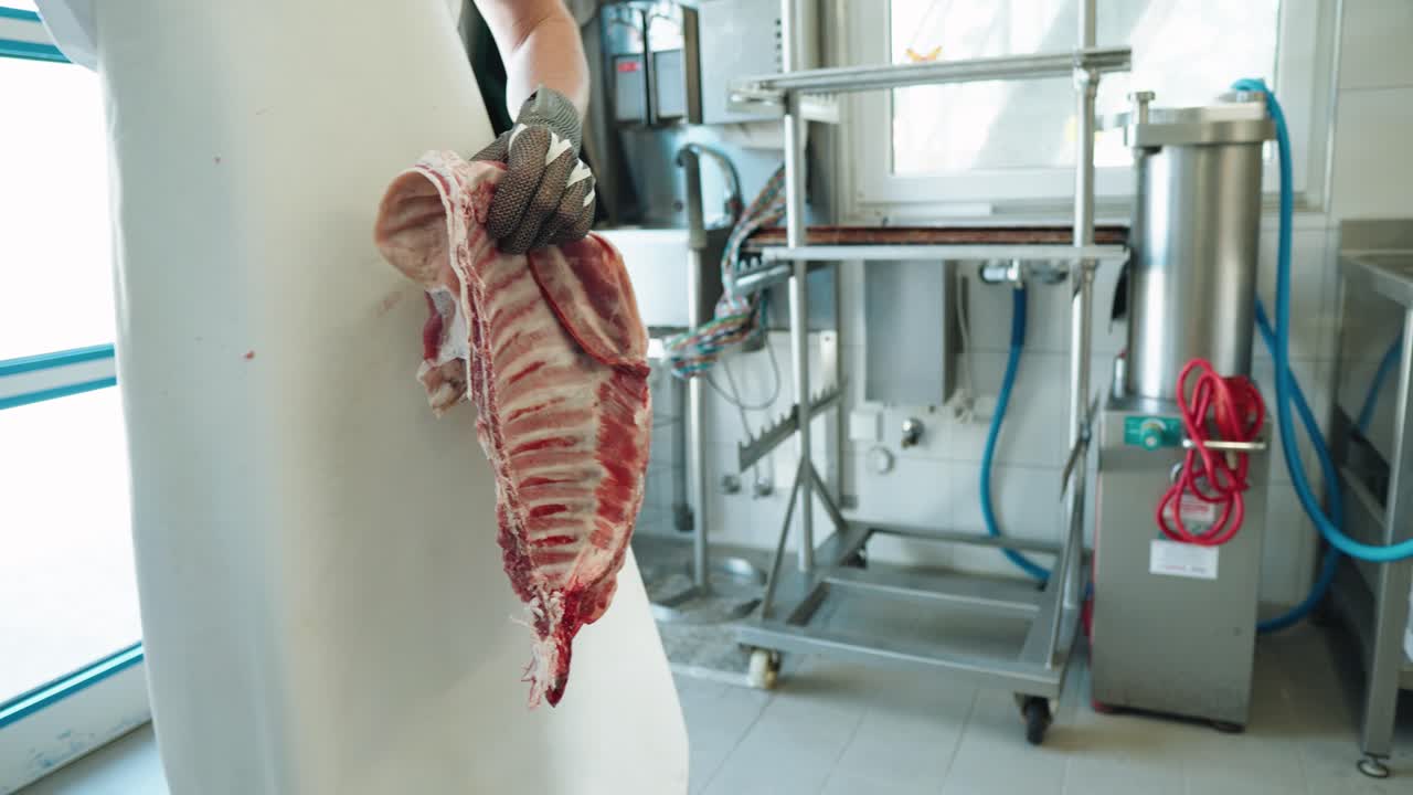 Butcher Using Saw To Cut Through Ribs of Hanging Lamb