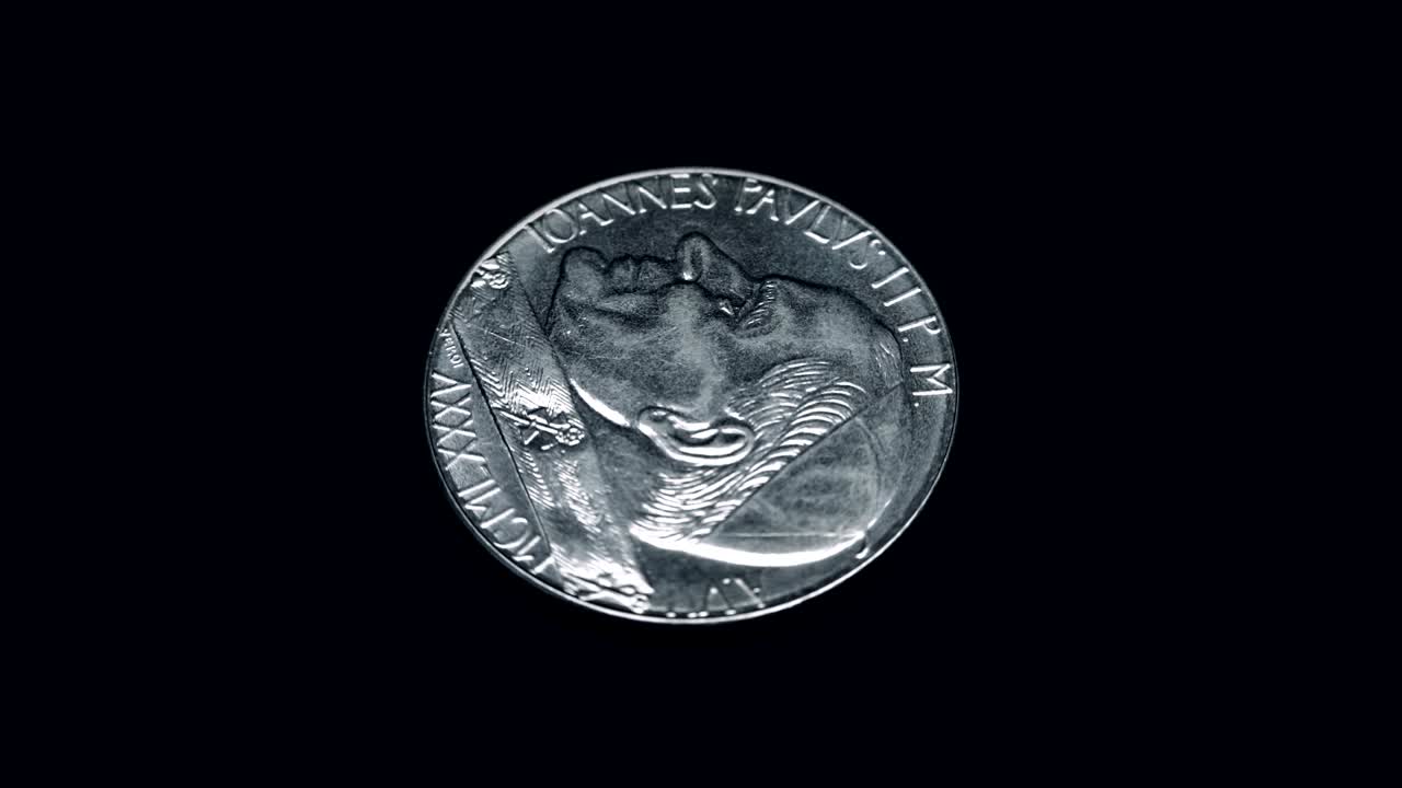 Coin IOANNES PAVLVS II P M A VII MCMLXXXV citta del vaticano 100 lire rotates on a black background. Macro. Closeup