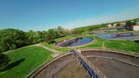 drone fpv vuelo bajo sobre una planta industrial de tratamiento de agua con contenedores de agua en un día soleado