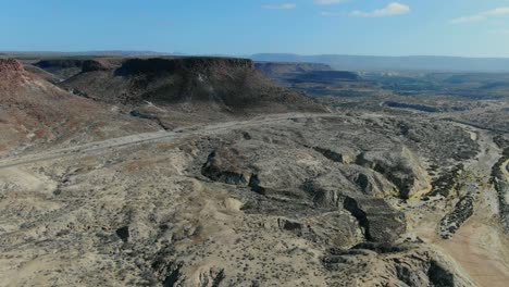 vista aérea en movimiento hacia adelante, vista panorámica del paisaje rocoso en la purísima baja california sur, méxico, furgoneta estacionada en medio de la carretera en un día soleado en el fondo