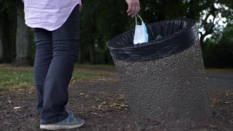 Woman-dropping-face-mask-into-a-bin-medium-shot