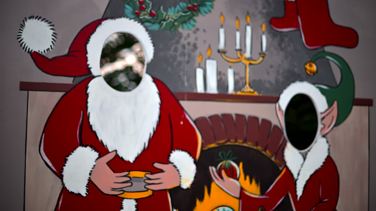 Festive Christmas stand-in board featuring Santa Claus and an elf with face cut outs