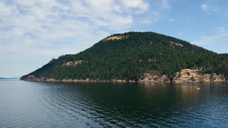 green and hilly island, boat view, on a sunny day with blue sky and clouds