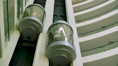 toma panorámica interior de los ascensores de un condominio residencial o de un hotel, con gente subiendo